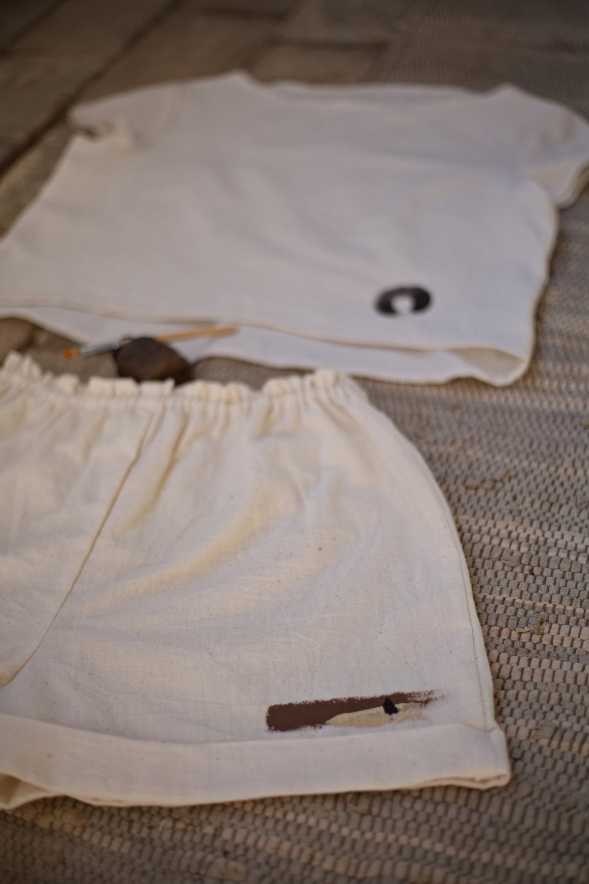 Művészi, wabi-sabi stílusú hangulatkép egy kézzel szőtt khadi rövidnadrágról és a hozzáillő felsőről, nyers földpigment részletekkel.